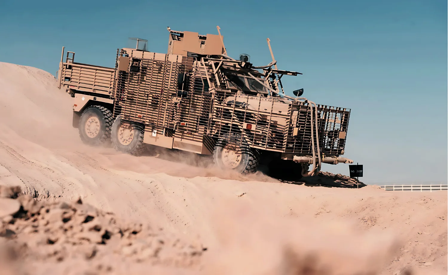 Armoured patrol vehicle climbing a desert slope